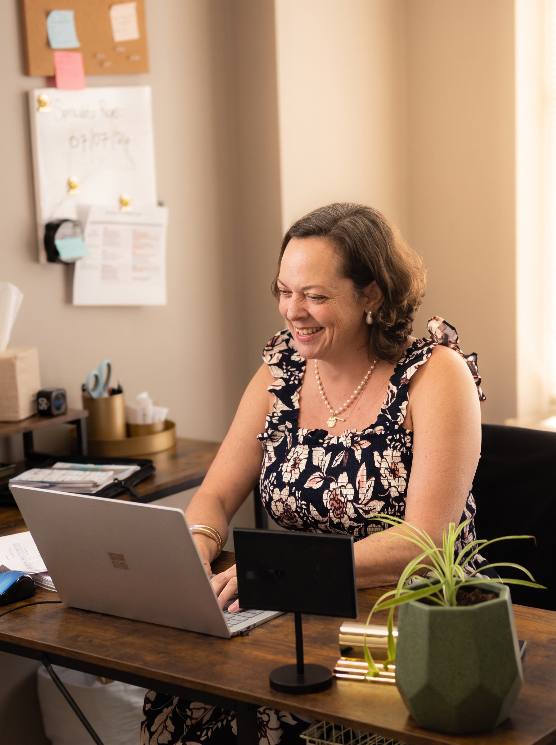 Jenny Gerow smiling at her desk while assisting a patient over the phone.